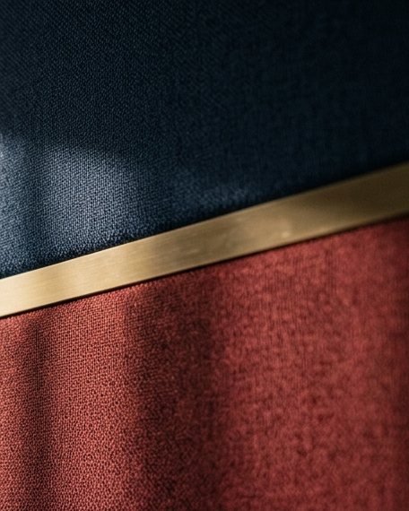 Close view of navy and maroon fabric wall panels divided by brass trims